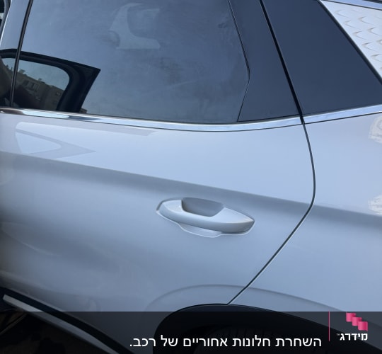 חלון צד כהה של רכב עם ידית דלת לבנה